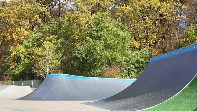 Ein Mann, der mit Inlineskates auf einer Halfpipe in einem Skatepark f&auml;hrt. Der Mann tr&auml;gt einen Helm und f&uuml;hrt einen Trick aus. Die Rampe ist aus Holz und gebogen.