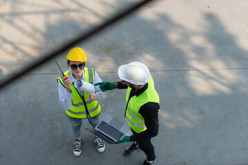 Overhead view on a building site, an engineer and architect are discussing on a laptop.