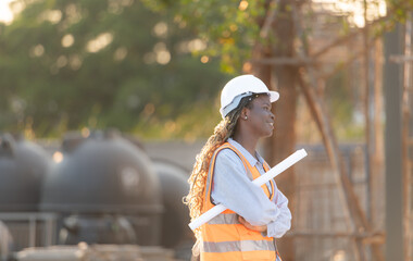 At the building site, a female engineer holds a blueprint in hand.