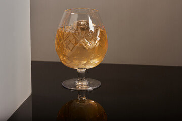 Glass of brandy and ice with a reflection on the surface.