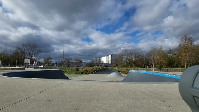 Ein Mann, der mit Inlineskates auf einer Halfpipe in einem Skatepark f&auml;hrt. Der Mann tr&auml;gt einen Helm und f&uuml;hrt einen Trick aus. Die Rampe ist aus Holz und gebogen.