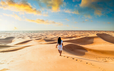Fototapeta na wymiar Dubai desert sand dunes, an Asian woman on Dubai desert safari, United Arab Emirates vacation, woman on vacation in Dubai walking at the sand dunes of Dubai 