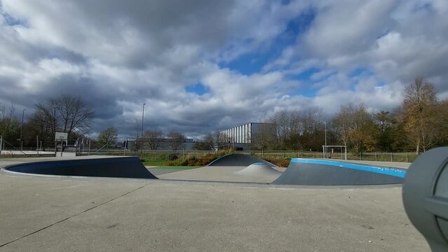Ein Mann, der mit Inlineskates auf einer Halfpipe in einem Skatepark f&auml;hrt. Der Mann tr&auml;gt einen Helm und f&uuml;hrt einen Trick aus. Die Rampe ist aus Holz und gebogen.