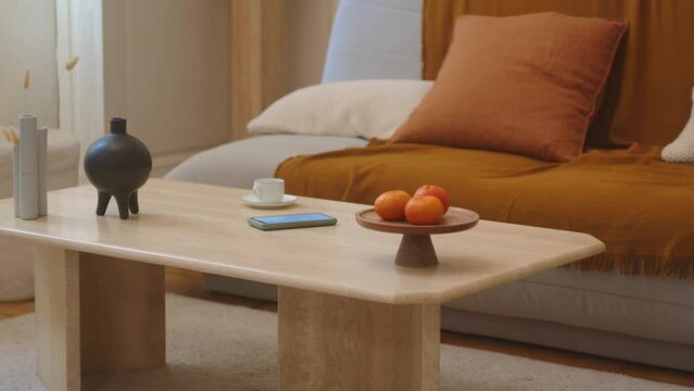 Woman in jeans walking into living room picking up cell phone from coffee table