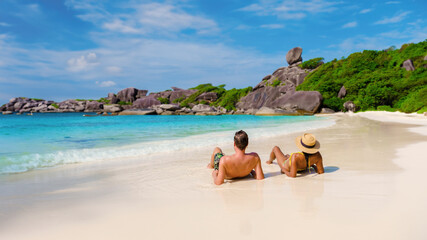 A couple of Asian women and white men relaxing on the beach in the sun at the Similan Islands in...