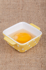 one raw egg yolk in bowl on table