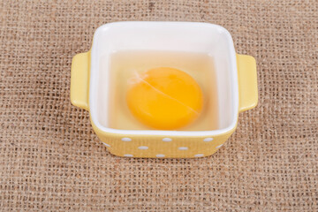 one raw egg yolk in bowl on table