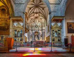 Altar and chapels inside the medieval church of San Francisco, part of the Chapel of Bones. Altar with saints and crucified Jesus Christ with colored lighting. - obrazy, fototapety, plakaty
