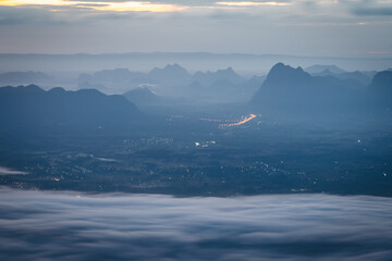 Sunrise over mountain range and night city with sea of cloud, fantastic light, dramatic cloud  and...