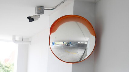 The curved glass with securit camera is installed at the corner of the parking building to prevent accidents from driving in the opposite direction - obrazy, fototapety, plakaty
