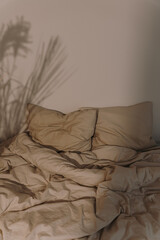 Aesthetic minimalist bedroom interior. Crumpled tan beige bed linens with warm soft sunlight shadows