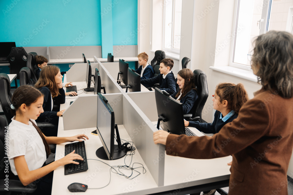 Wall mural group of school kids using personal computers during computer science class with teacher