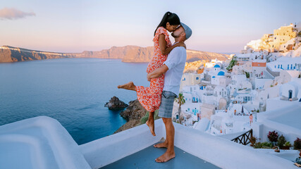 Santorini Greece, a young couple on luxury vacation at the Island Santorini watching the sunrise by the blue dome church and whitewashed village Oia Santorini during summer holidays - obrazy, fototapety, plakaty