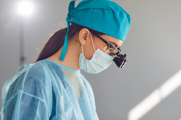 Close up portrait of a young woman doctor dentist with dental binocular loupes on her face wearing...