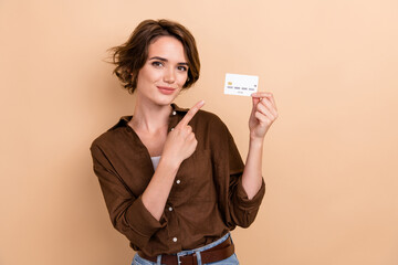 Portrait of clever cheerful girl with bob hairstyle wear stylish shirt directing at credit card in...