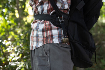 A person who wear a backpack with bear bell at the green forest in Autumn