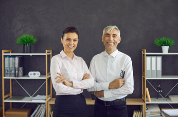 Family Business Succession: Cheerful young woman and elderly man in white office shirts standing...