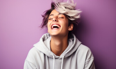 Radiant Young Person with Short Hair Laughing Joyfully in a Casual Hoodie Against a Soft Purple Background, Exuding Happiness and Youthful Energy