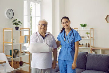 Portrait of happy injured senior male patient together with female doctor. Old man with arm sling...