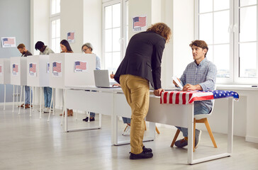 Back view portrait american man with long hair registering at polling station with American flags...