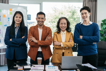 Business team smiling and confident standing in front of bright desk.