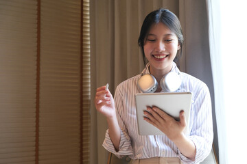 Attractive millennial Asian woman using her digital tablet in the coffee shop. remote working, urban lifestyle concept