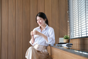 A beautiful girl with a smile on her face communicates with colleagues online, on a laptop