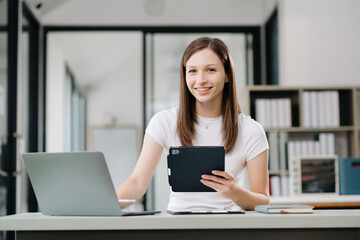 Confident business expert attractive smiling young woman holding digital tablet  on desk in office..