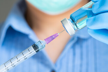 doctor's hand holds a syringe and a blue vaccine bottle at the hospital. Health and medical...