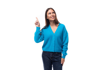 young active caucasian woman with black hair dressed in a blue cardigan and jeans points with her hands to have an idea on a white background