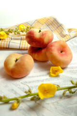 Several whole saturn peaches or flat peach on white wooden background..