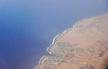 resort between blue sea and desert view during a flight on vacation