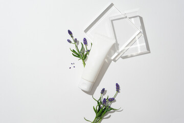 An unlabeled cosmetic tube decorated with lavender flowers and two glass platforms. White background for text design. Essential oils made from lavender flowers and leaves help heal wounds.