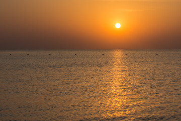 Obraz premium warm sunrise with reflections in the sea with waves and buoys