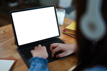 Closeup child girl hands typing on keyboard of digital tablet while doing homework at dinning table