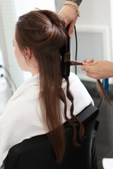 The hairdresser prepares the woman, styles her hair in the form of curls. Curling hair in the...