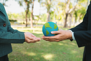Earth day concept, businessman giving Earth globe to colleague as CSR corporate social responsible...