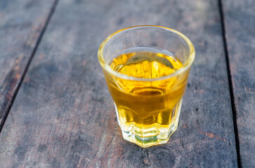 Small shot glass of alcoholic drink on the old wooden bar counter. Selective focus.