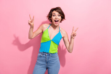Photo of pretty excited lady wear green blue tank top showing two v-signs empty space isolated pink...