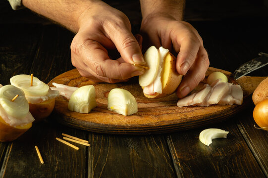 Cooking lard and potatoes with onions on the kitchen table by the hands of a chef. The concept of preparing a Ukrainian national dish called parusa
