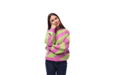 young slender caucasian woman with straight black hair dressed in a striped pink pullover posing on a white background