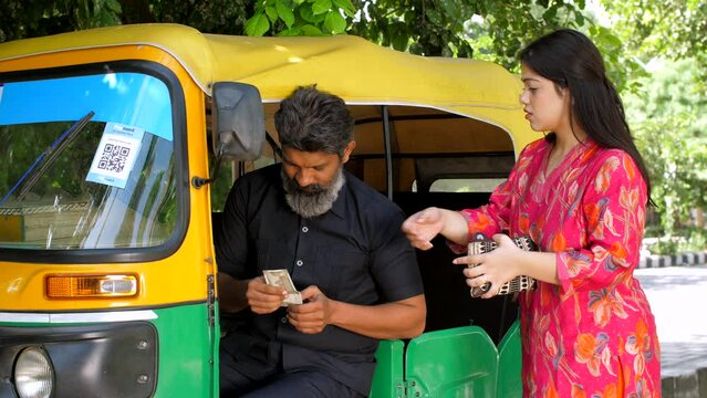 An office-going girl paying money to an auto rickshaw driver - Indian currency exchange  transportation  cash transaction. Indian woman using public transportation: auto-rickshaw journey  passenger...