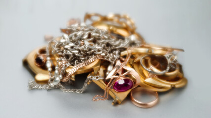 Old and broken jewelry, watches of gold and gold-plated lies in a pile. A scrap of precious metals In soft focus. Selective focus. - obrazy, fototapety, plakaty