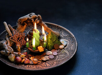 money magic. Witch altar with candles, old coins, stone runes, pentacle on dark table close up....