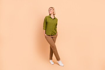 Fototapeta na wymiar Full size photo of positive pretty girl wear khaki shirt brown trousers look at sale empty space isolated on pastel color background