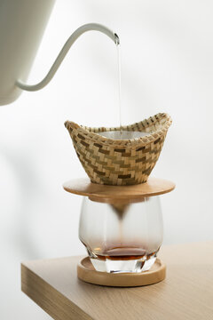Pour hot water onto the ground coffee in a dripper made of bamboo weave.