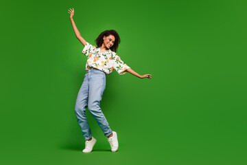 Full length photo of cheerful pretty lady wear print shirt dancing empty space isolated green color background