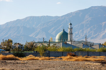 Al Amin mosque in Balykchy, Kyrgyzstan in front of mountains at sunny autumn day.