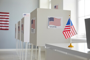 Empty polling station with row of white voting booths decorated with American flag at vote center....