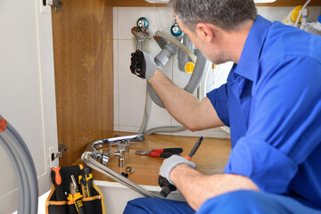 Plumber making a repair in the kitchen of a house